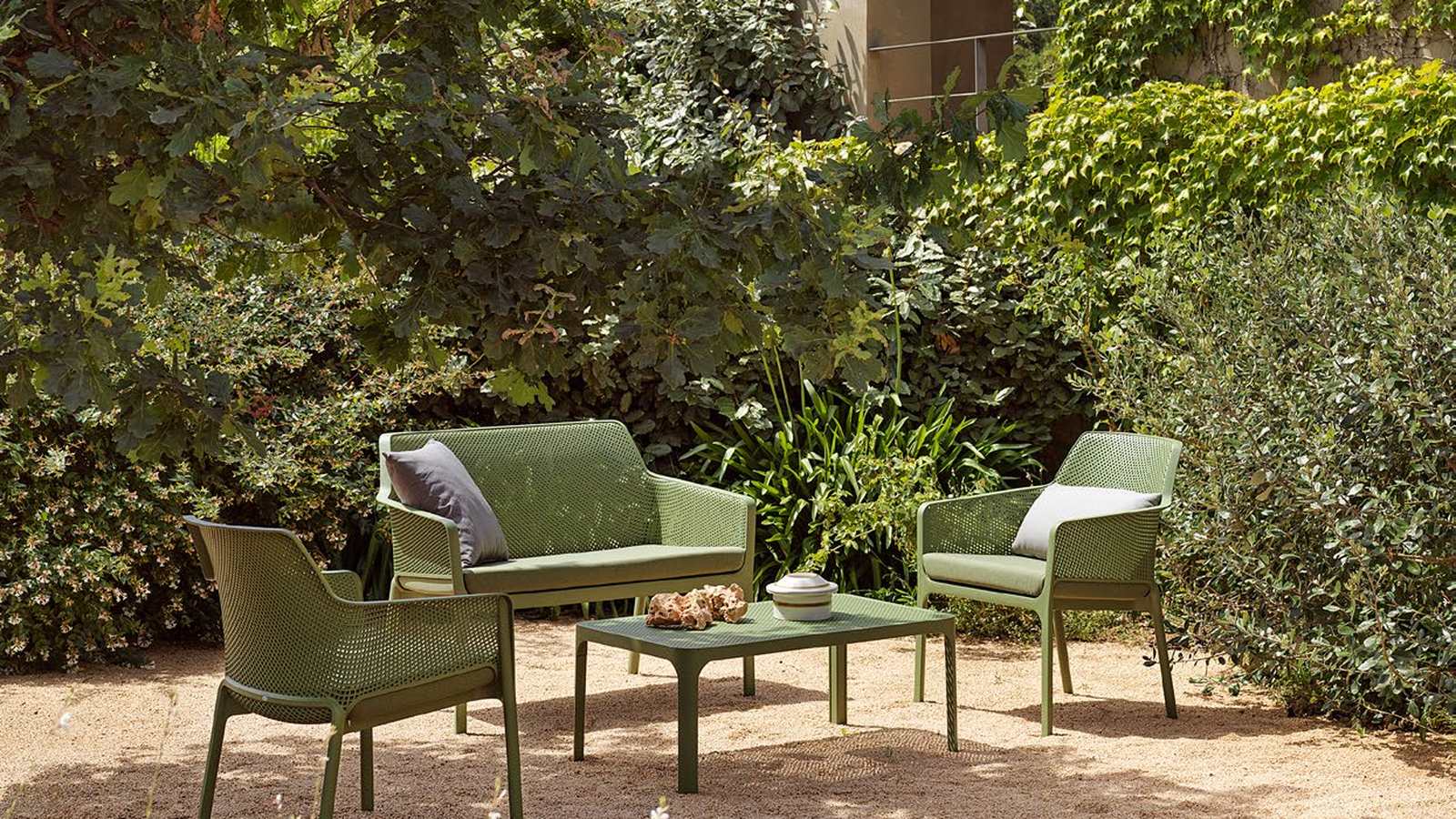 Nardi Net Bench and Net Relax chairs in Agave with giungla Sunbrella cushions around a Net Table 100 in a garden