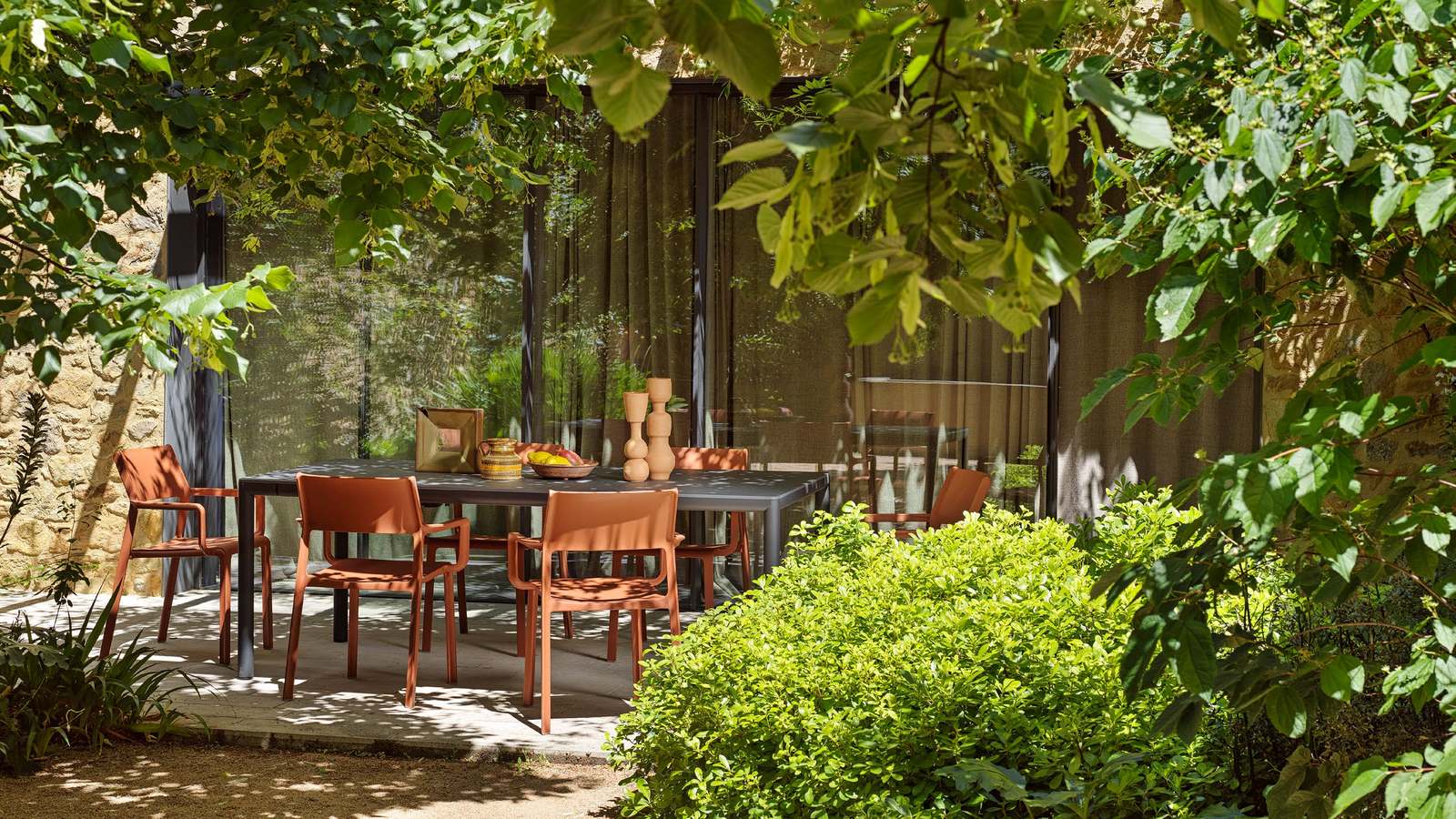 Nardi Tevere Lam 210 extendable table in Antracite with Trill armchairs in the new Mattone colour in a shaded garden